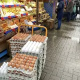 Duże stosy jajek na targu. Widać różne rodzaje i kolory, a także ceny.