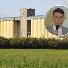 Mężczyzna w okularach przemawia na tle silosów zbożowych. Dyskusja o przyszłej cenie pszenicy 2025.