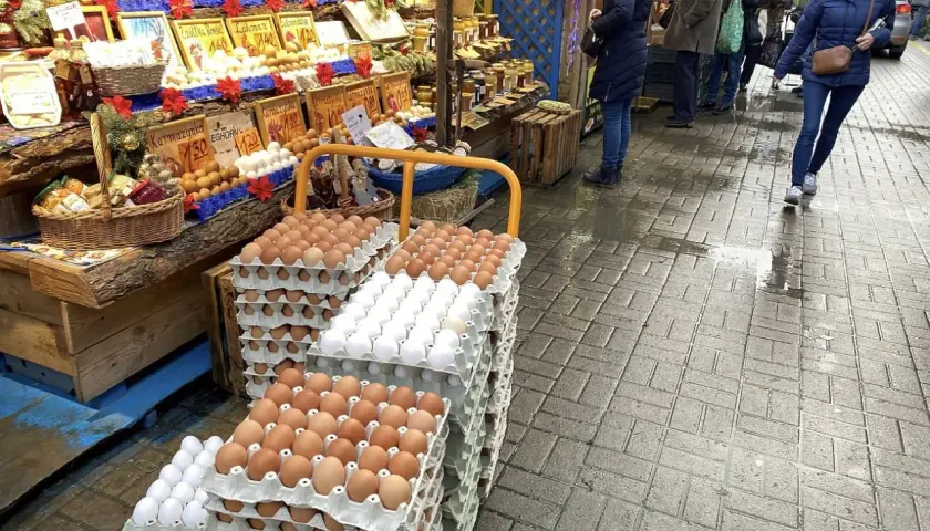 Duże stosy jajek na targu. Widać różne rodzaje i kolory, a także ceny.