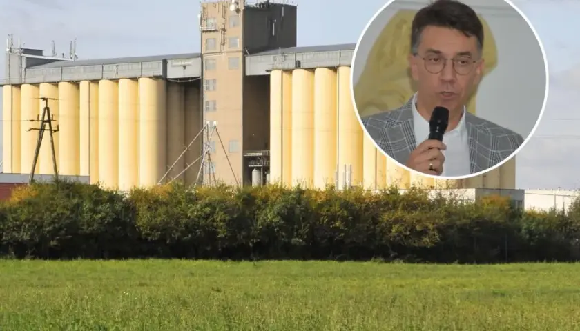 Mężczyzna w okularach przemawia na tle silosów zbożowych. Dyskusja o przyszłej cenie pszenicy 2025.
